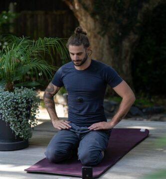 a man sitting on a yoga mat with his hands in his pockets